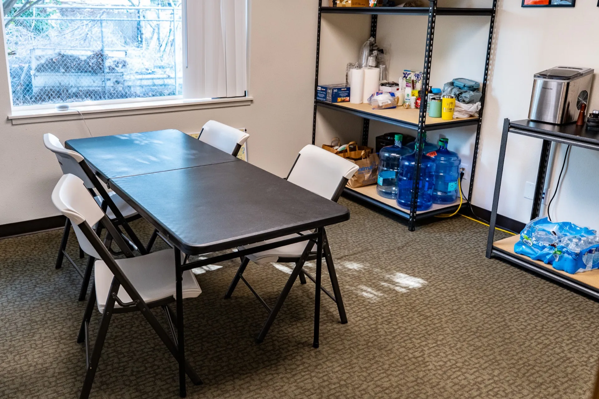The same break room after cleaning, with a cleared table, tidy chairs, and organized shelves
