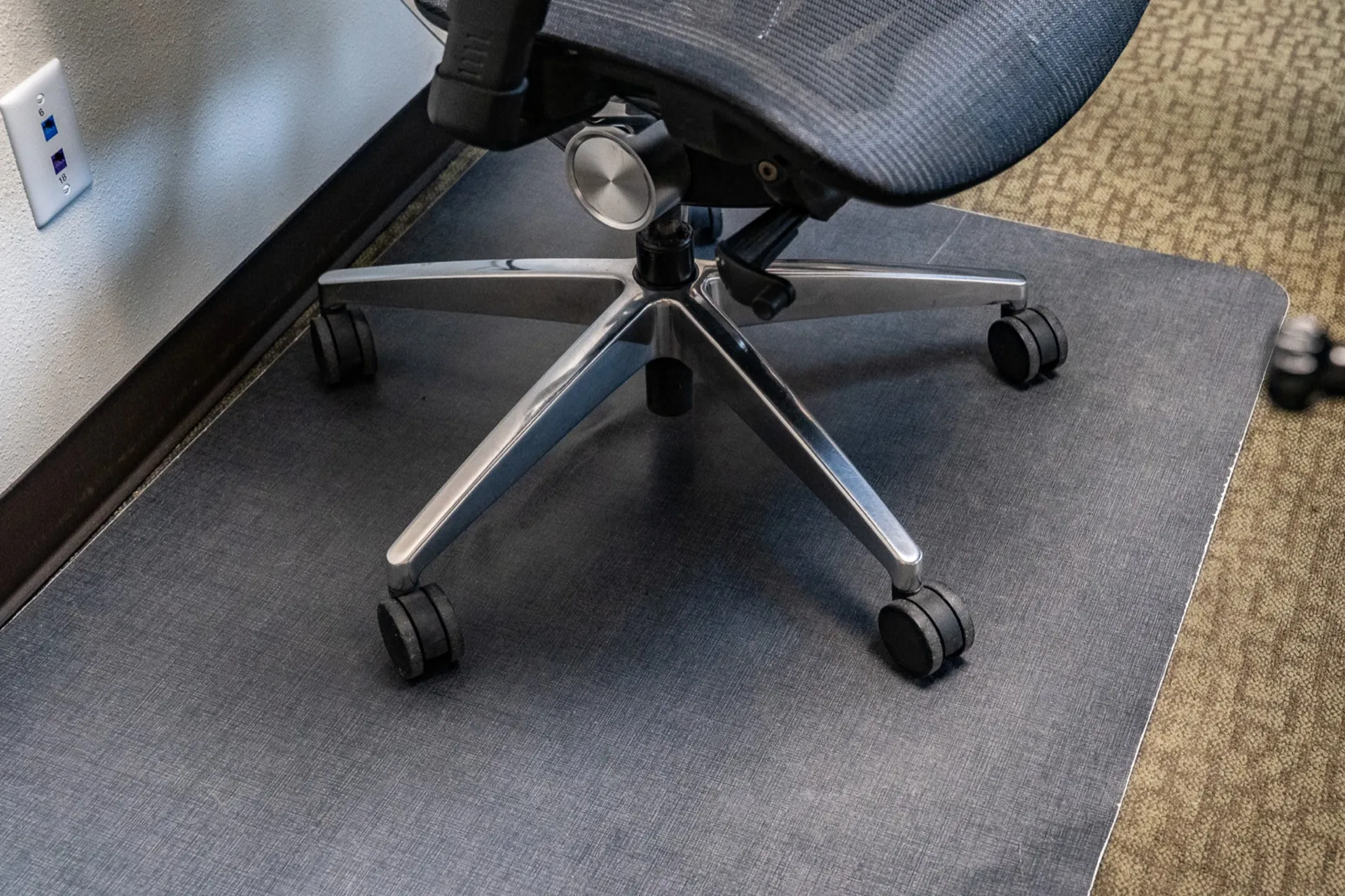The same office chair base spotless after cleaning, with a dust-free mat and polished casters